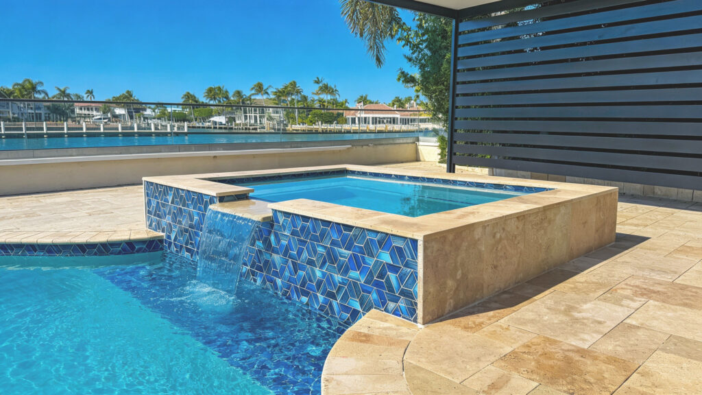 Raised spa with blue glass tile on a waterfront pool deck